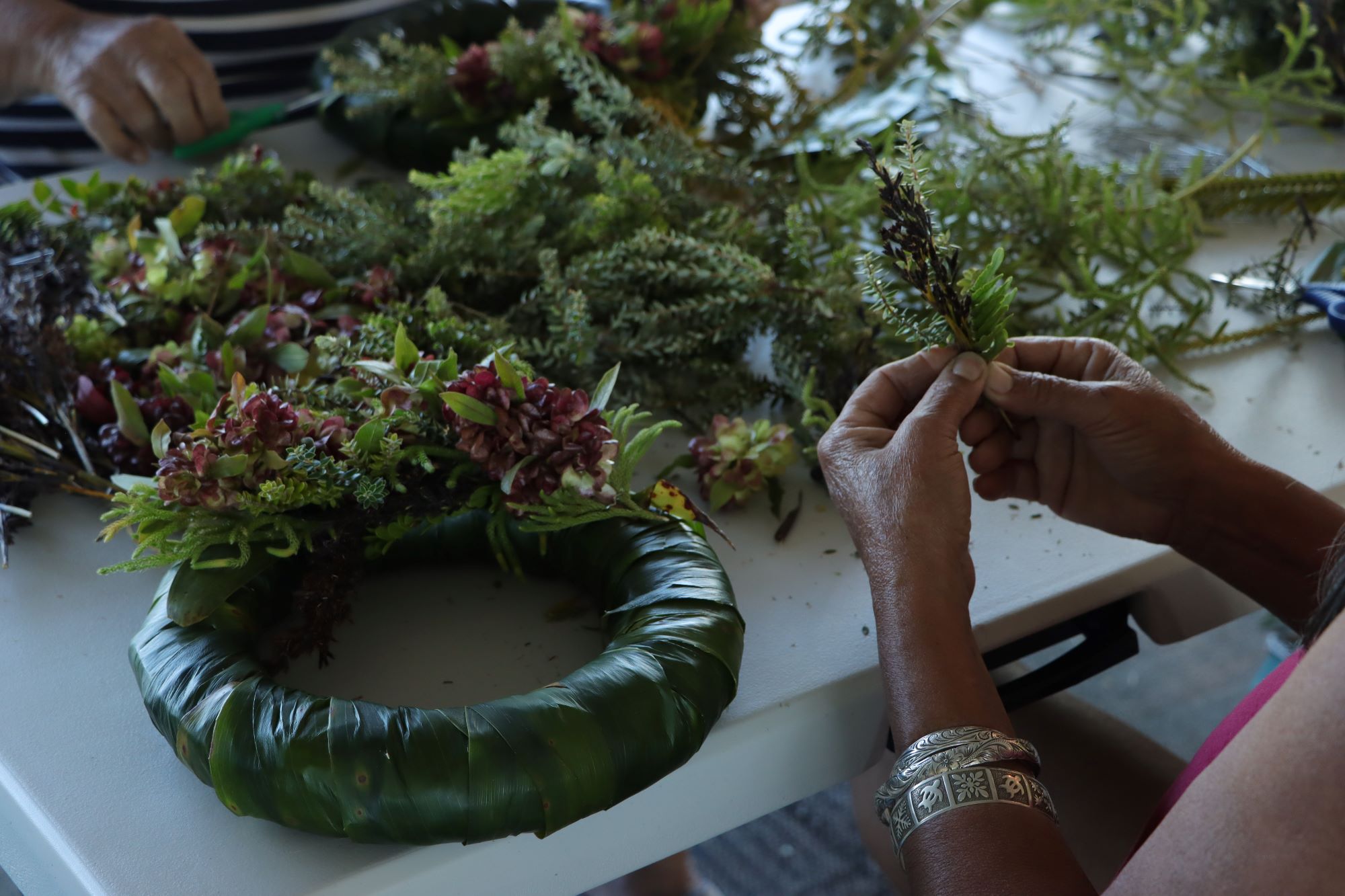 A semi-finished wreath with someone holding a medium bundle.